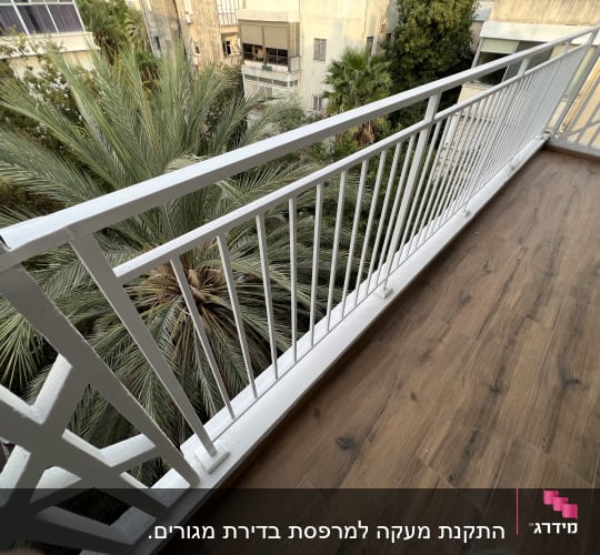 מעקה מתכת לבן על מרפסת עץ
